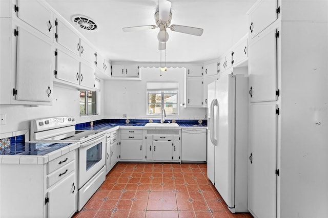 kitchen featuring white appliances, a sink, tile patterned flooring, tile counters, and white cabinetry