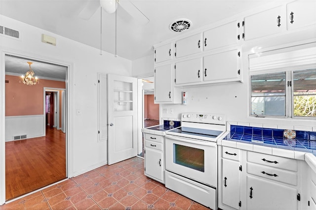 kitchen with tile countertops, visible vents, white electric range oven, and white cabinetry