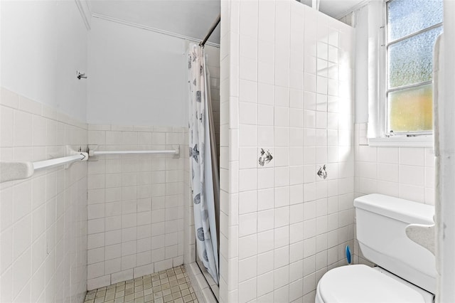 bathroom featuring toilet, tile walls, wainscoting, and a tile shower