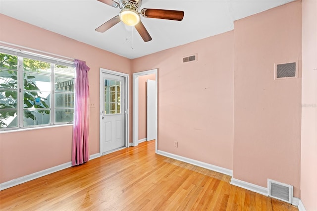 empty room with visible vents, light wood-type flooring, and baseboards