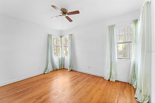 unfurnished room with a wealth of natural light, baseboards, light wood-style floors, and a ceiling fan