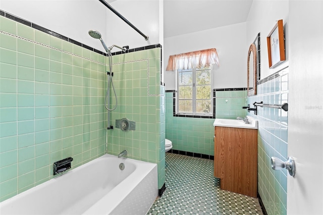 full bathroom featuring vanity,  shower combination, wainscoting, tile walls, and toilet