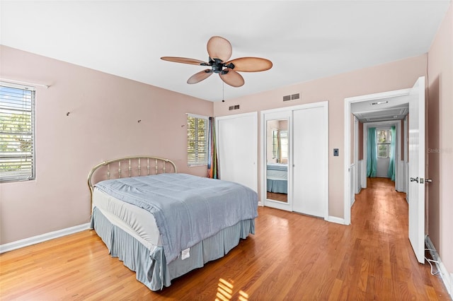 bedroom featuring visible vents, multiple windows, and light wood-style floors