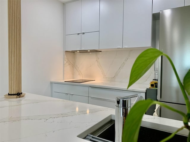 kitchen with light stone counters, decorative backsplash, white cabinets, and modern cabinets