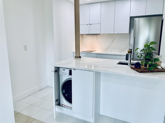 interior space with light stone counters, washer / clothes dryer, backsplash, freestanding refrigerator, and white cabinets