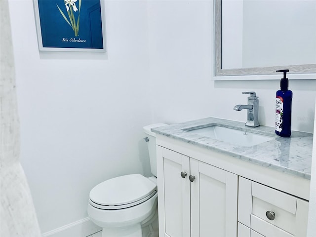 half bathroom featuring vanity, toilet, and baseboards
