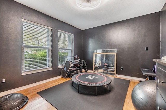 rec room featuring baseboards, wood finished floors, and a textured wall