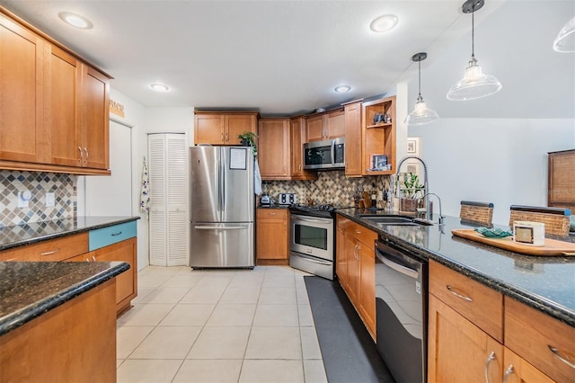 kitchen featuring dark stone countertops, light tile patterned floors, a sink, appliances with stainless steel finishes, and brown cabinets