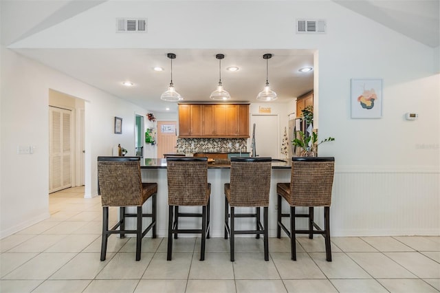 kitchen featuring dark countertops, visible vents, a peninsula, and a kitchen bar