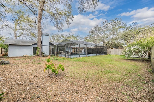 rear view of house featuring glass enclosure, an outdoor pool, a chimney, fence private yard, and a lawn