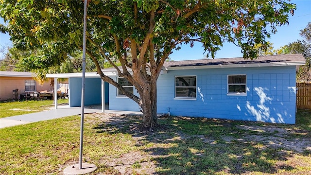 view of side of home featuring a carport, a yard, and fence