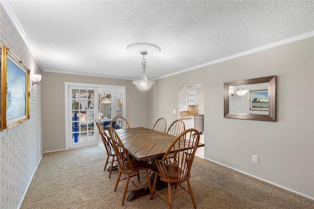 carpeted dining room with arched walkways, a textured ceiling, baseboards, and ornamental molding