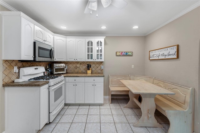 kitchen featuring stainless steel microwave, white cabinets, light tile patterned floors, and white range with gas cooktop