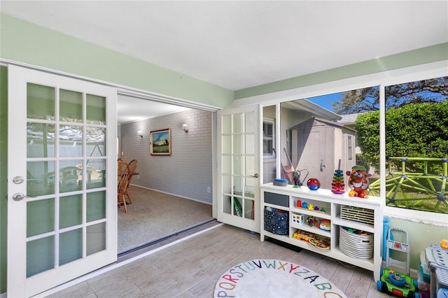 recreation room featuring wood finished floors and brick wall