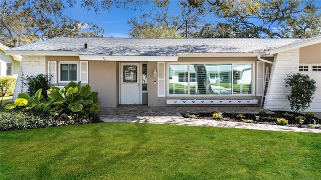 view of front of property with a front lawn, a garage, roof with shingles, and stucco siding