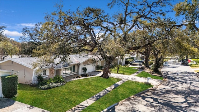 view of front facade with a front lawn, an attached garage, and driveway