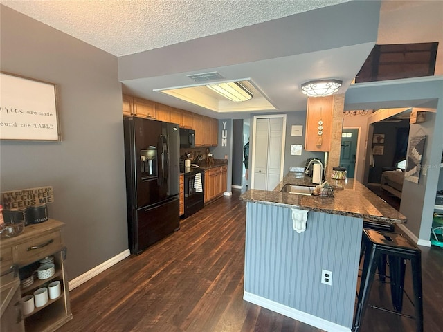 kitchen with visible vents, dark wood-type flooring, black appliances, a sink, and a raised ceiling