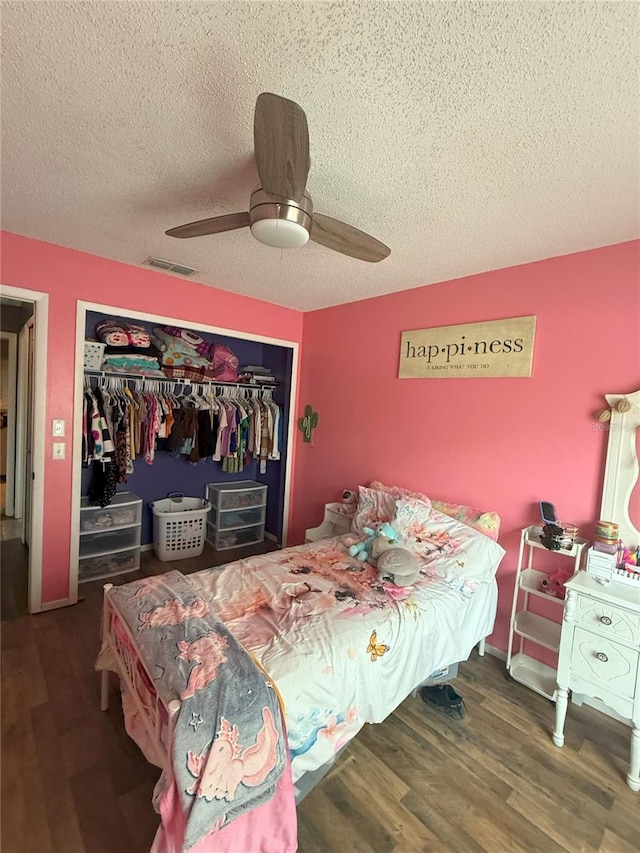 bedroom featuring visible vents, a textured ceiling, wood finished floors, a closet, and ceiling fan