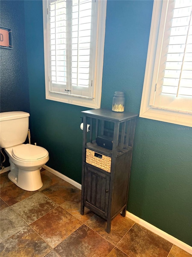 bathroom featuring a wealth of natural light, toilet, and baseboards