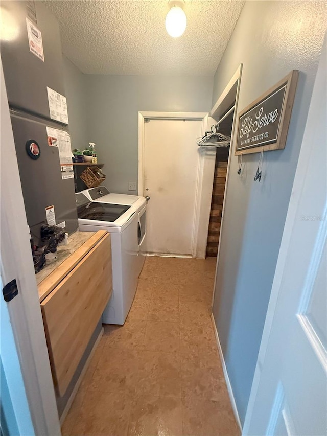 washroom featuring laundry area, light tile patterned floors, washing machine and dryer, and a textured ceiling