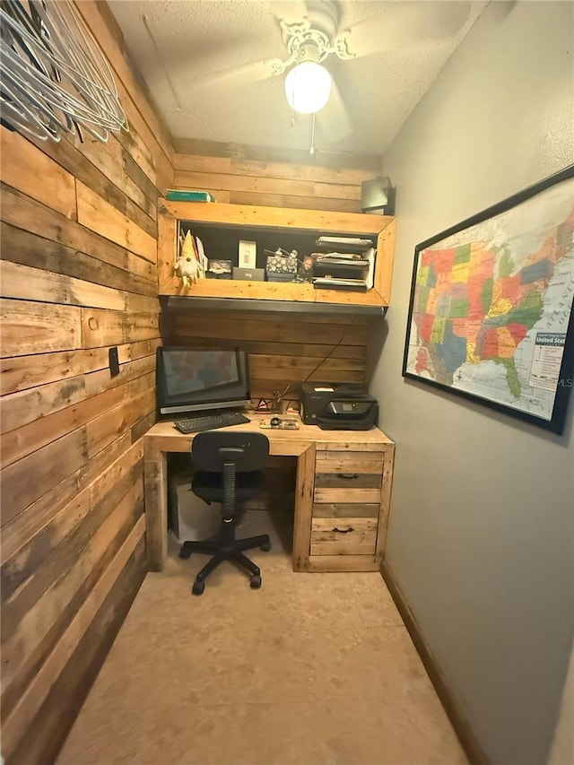 office space with a textured ceiling, wooden walls, and built in study area