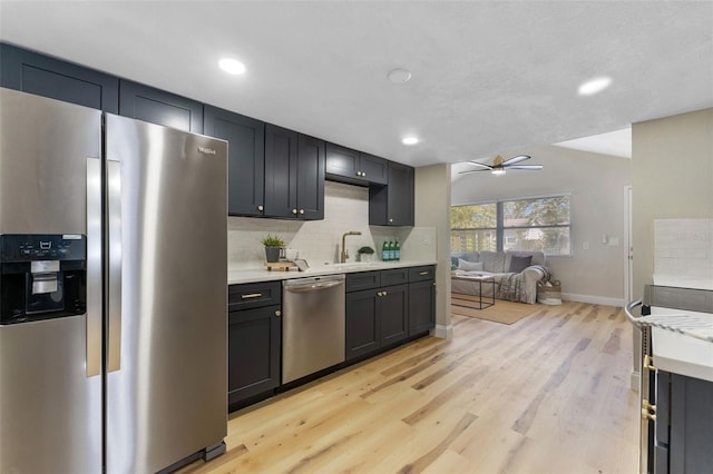 kitchen featuring light wood-type flooring, backsplash, stainless steel appliances, light countertops, and ceiling fan