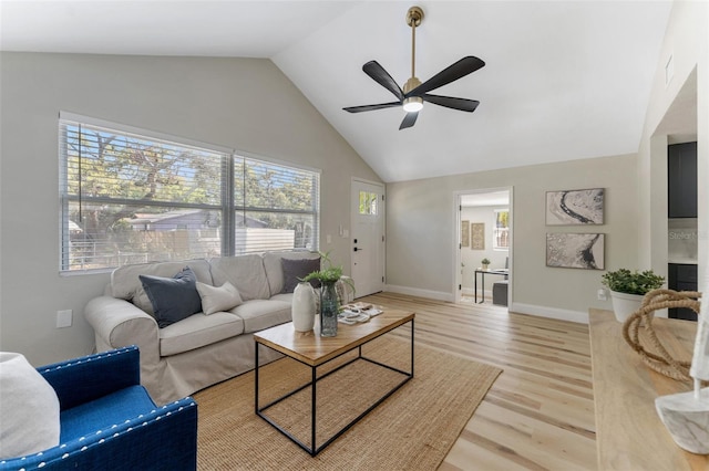 living room with a wealth of natural light, light wood-style flooring, high vaulted ceiling, and baseboards