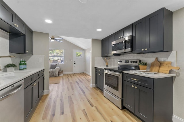 kitchen featuring baseboards, decorative backsplash, stainless steel appliances, and light wood-style floors