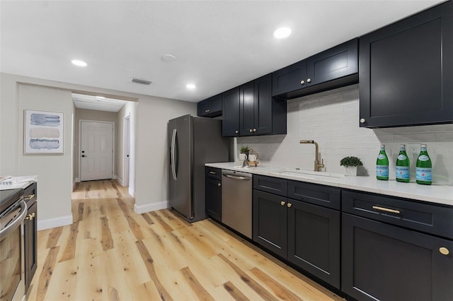 kitchen featuring visible vents, a sink, tasteful backsplash, appliances with stainless steel finishes, and light wood finished floors