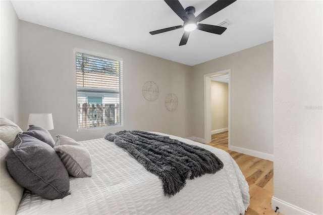 bedroom featuring light wood-type flooring, baseboards, visible vents, and ceiling fan