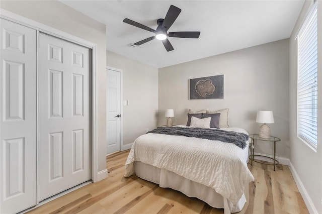 bedroom featuring baseboards, light wood-type flooring, a closet, and ceiling fan