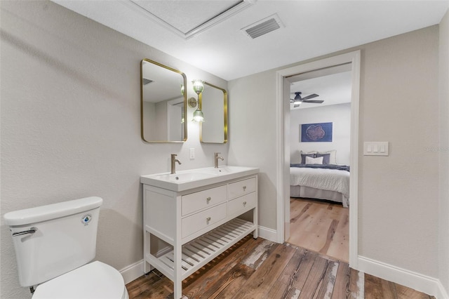 ensuite bathroom with wood finished floors, baseboards, visible vents, a sink, and toilet