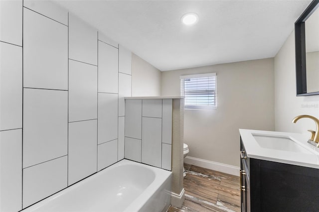 bathroom featuring toilet, vanity, baseboards, and wood finished floors