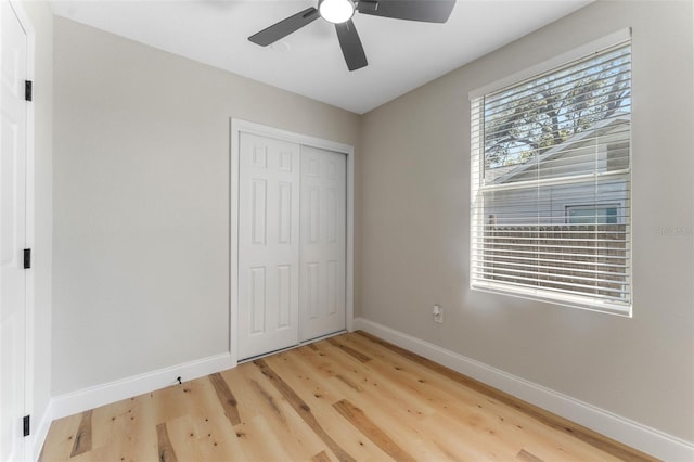 unfurnished bedroom featuring light wood-style flooring, a ceiling fan, baseboards, and a closet