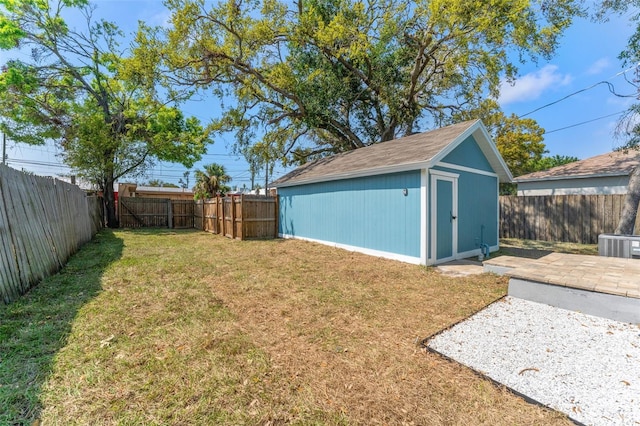 view of yard featuring an outbuilding, a patio, a storage unit, and a fenced backyard