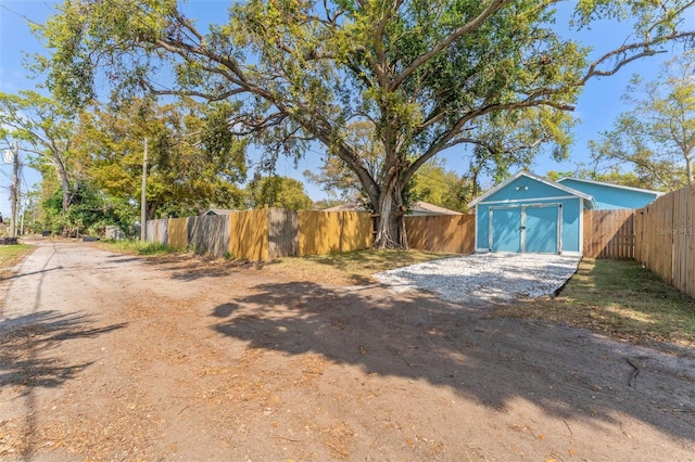 view of yard featuring a storage unit, an outdoor structure, a fenced backyard, and driveway