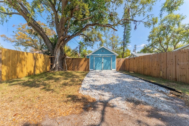 view of yard with a fenced backyard, a detached garage, a storage shed, and an outdoor structure