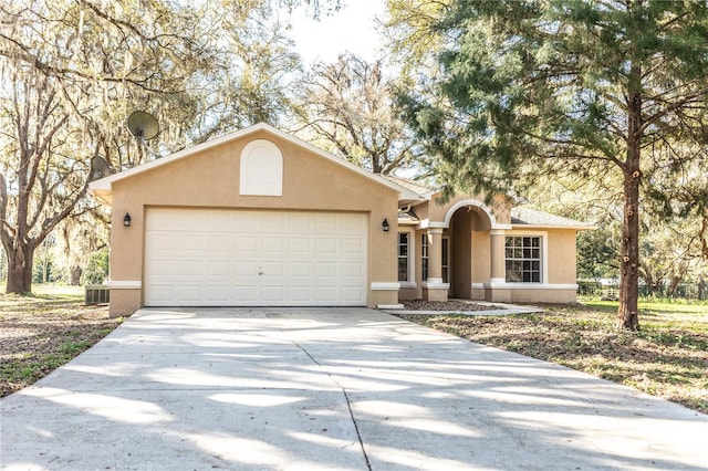 ranch-style home featuring concrete driveway, an attached garage, cooling unit, and stucco siding