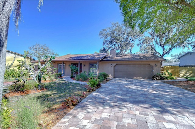 single story home featuring decorative driveway, fence, a garage, brick siding, and a chimney