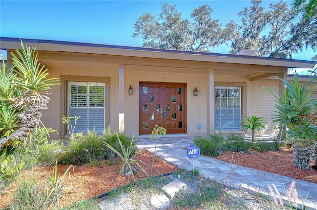 property entrance with an attached garage, covered porch, and brick siding