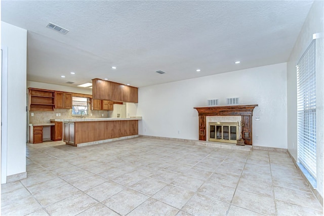 unfurnished living room with a glass covered fireplace, light tile patterned flooring, and visible vents