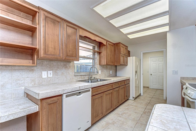 kitchen with a sink, decorative backsplash, brown cabinets, white appliances, and open shelves