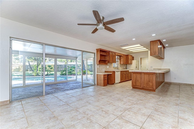 kitchen with light countertops, brown cabinets, a peninsula, white appliances, and open shelves