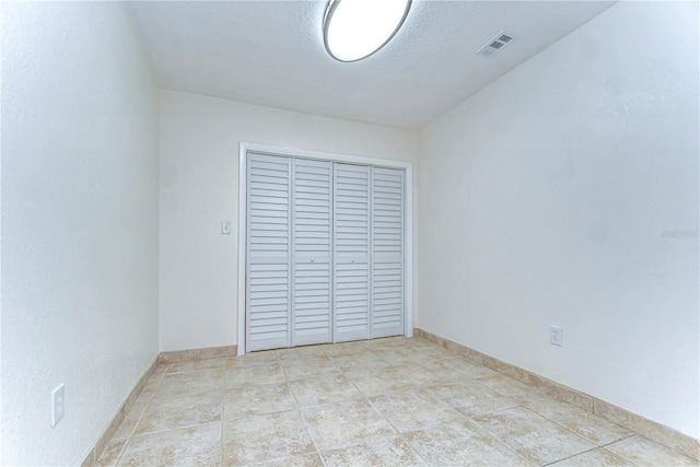 empty room with visible vents, baseboards, and a textured ceiling