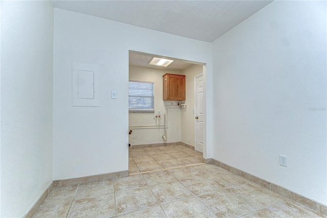 empty room featuring electric panel, light tile patterned floors, and baseboards