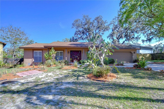 single story home with a front lawn, an attached garage, fence, and brick siding