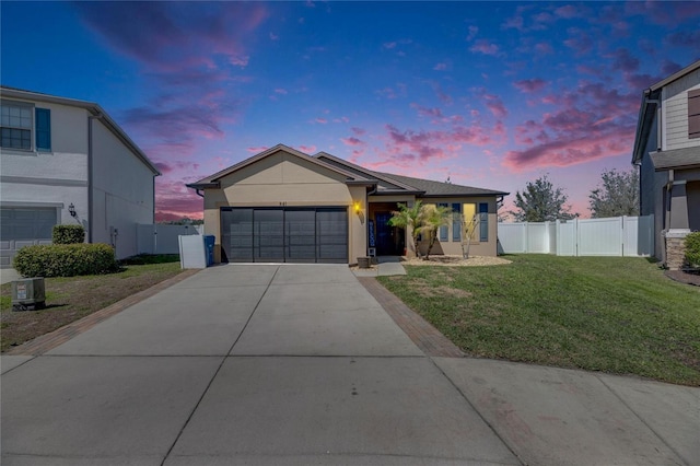 ranch-style home featuring a garage, a front lawn, driveway, and fence