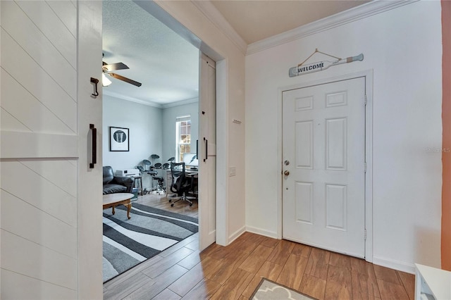 foyer entrance with crown molding, baseboards, light wood-type flooring, and ceiling fan