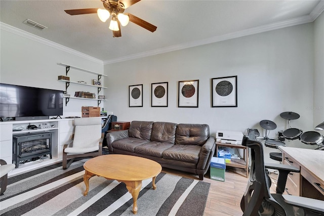 living area with visible vents, ornamental molding, a ceiling fan, and light wood-style flooring