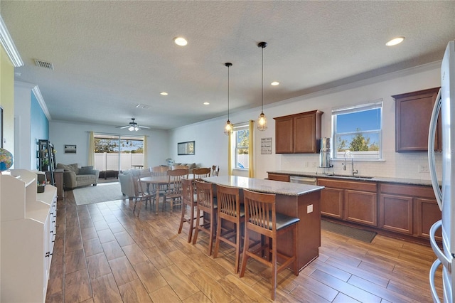 kitchen with a sink, tasteful backsplash, a center island, and wood tiled floor